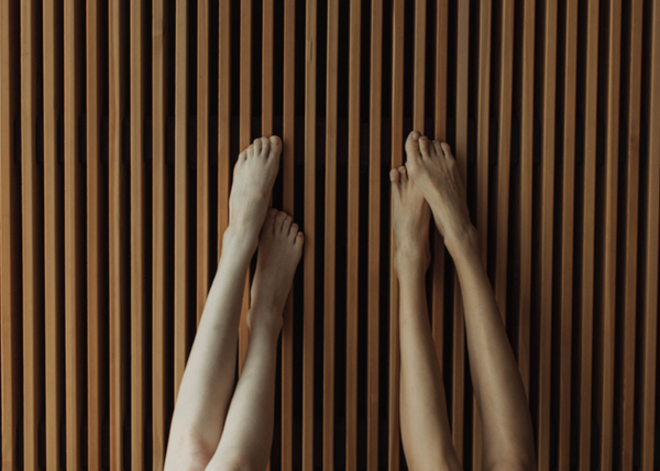 Two bare legs leaning against the wooden wall.
