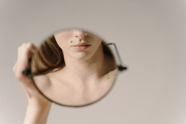 a woman looking at herself in a round mirror.